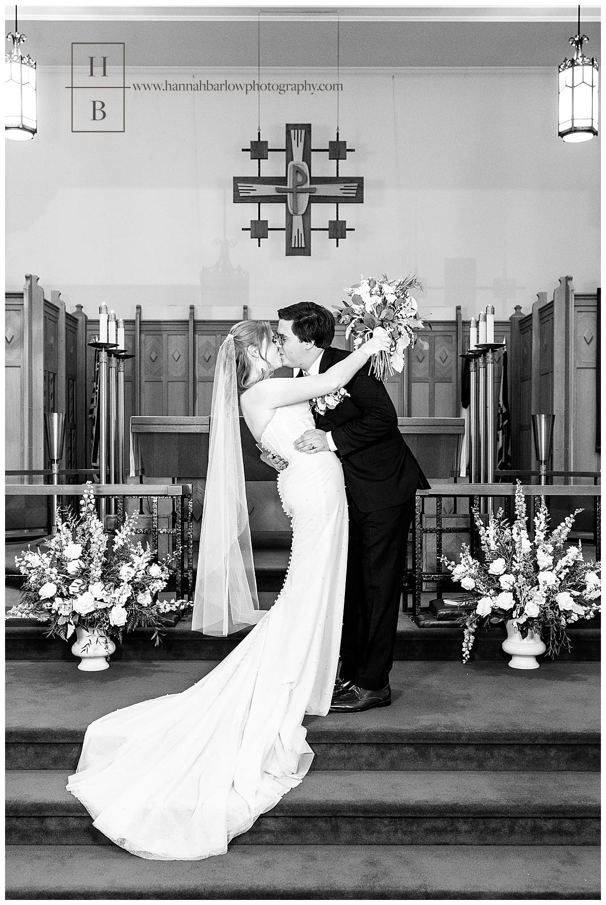 black and white photo of couple dipping and kissing at front of church
