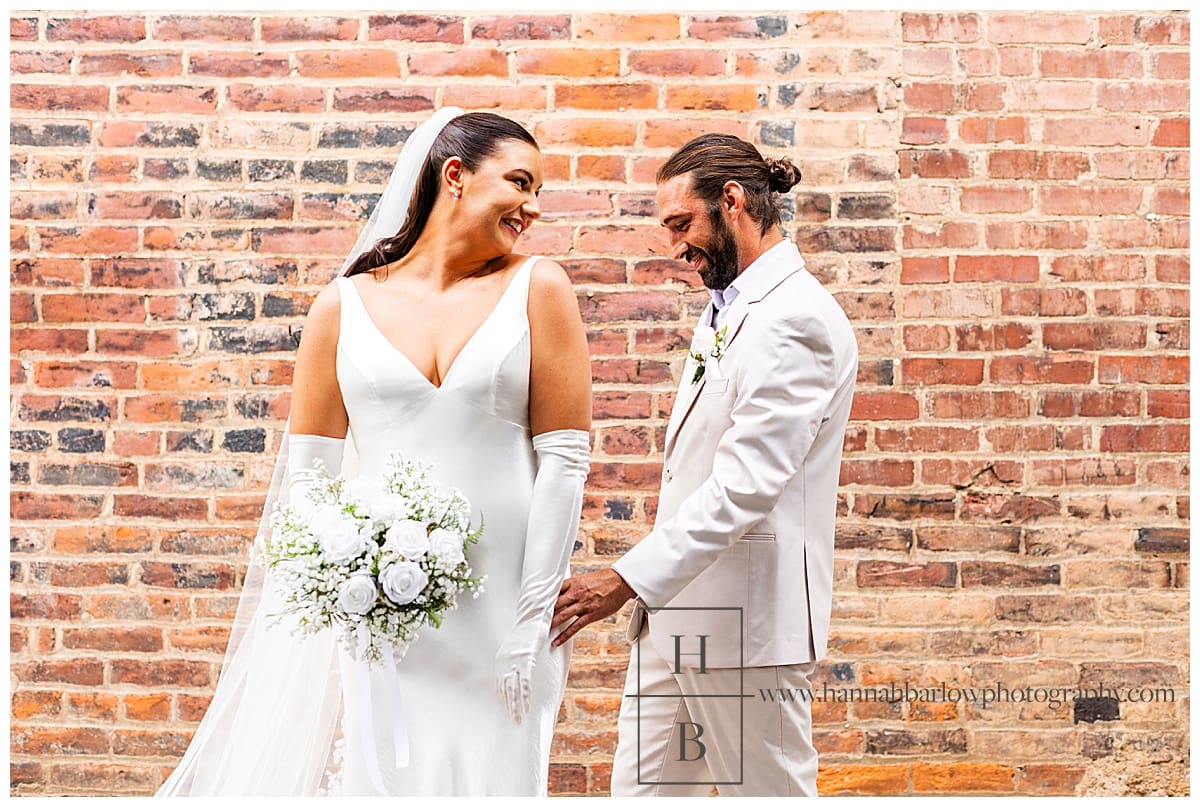 bride shows off back of her dress to groom