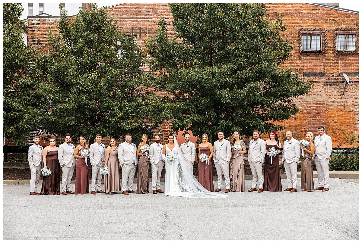 wedding party in different hues of brown and tan pose for full wedding party photo