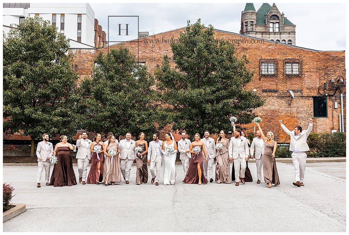 wedding party in coordinating hues of brown and tan walk and laugh