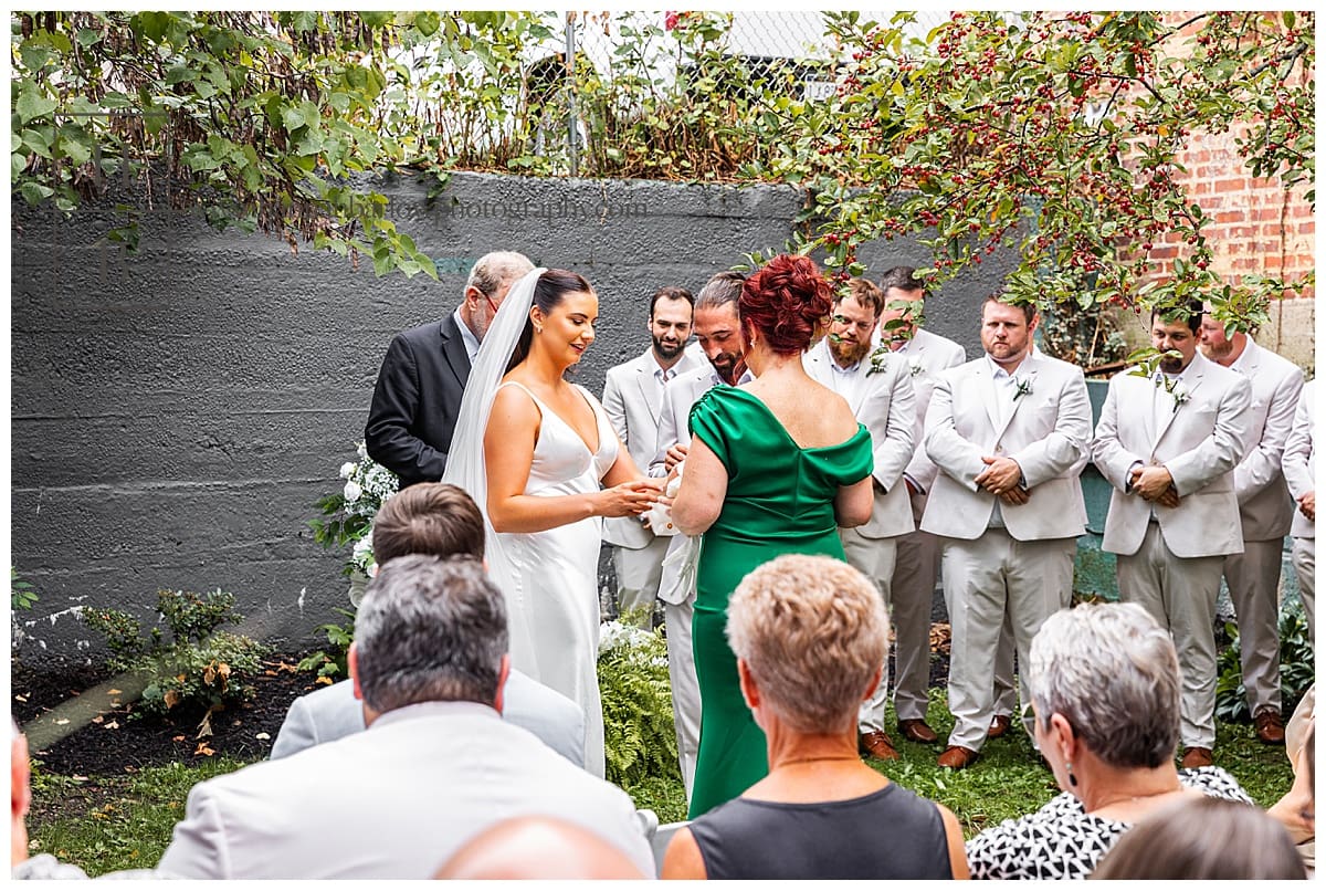bride hands gloves to mother of bride in green dress during ceremony