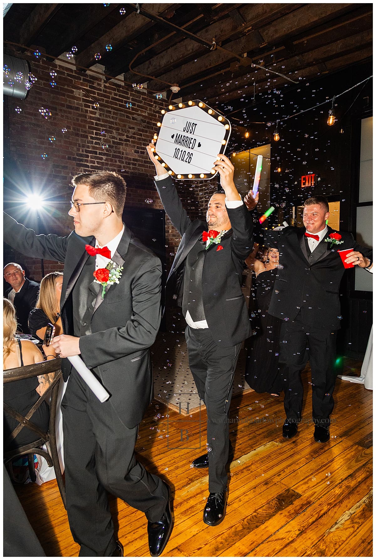 groomsmen hold signs celebrating while entering reception