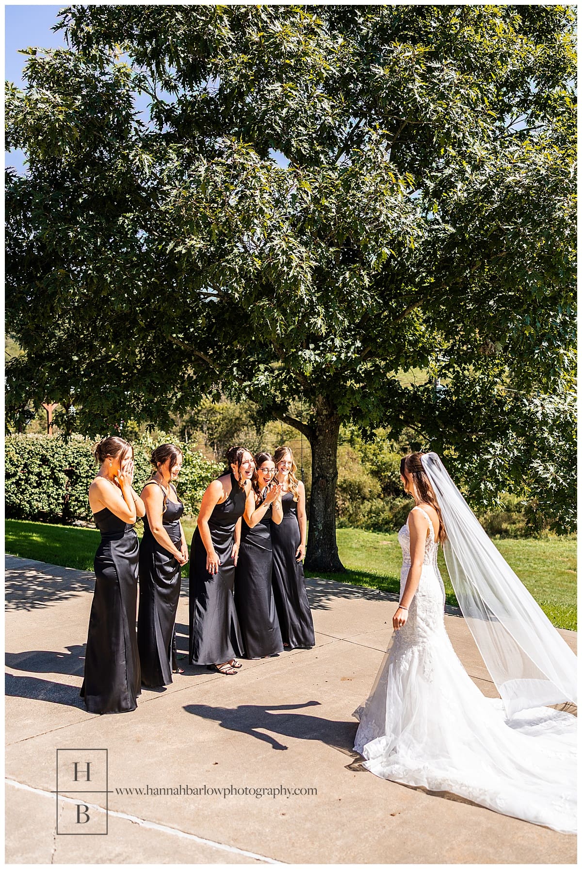 bridesmaids in black dresses look excited to see bride