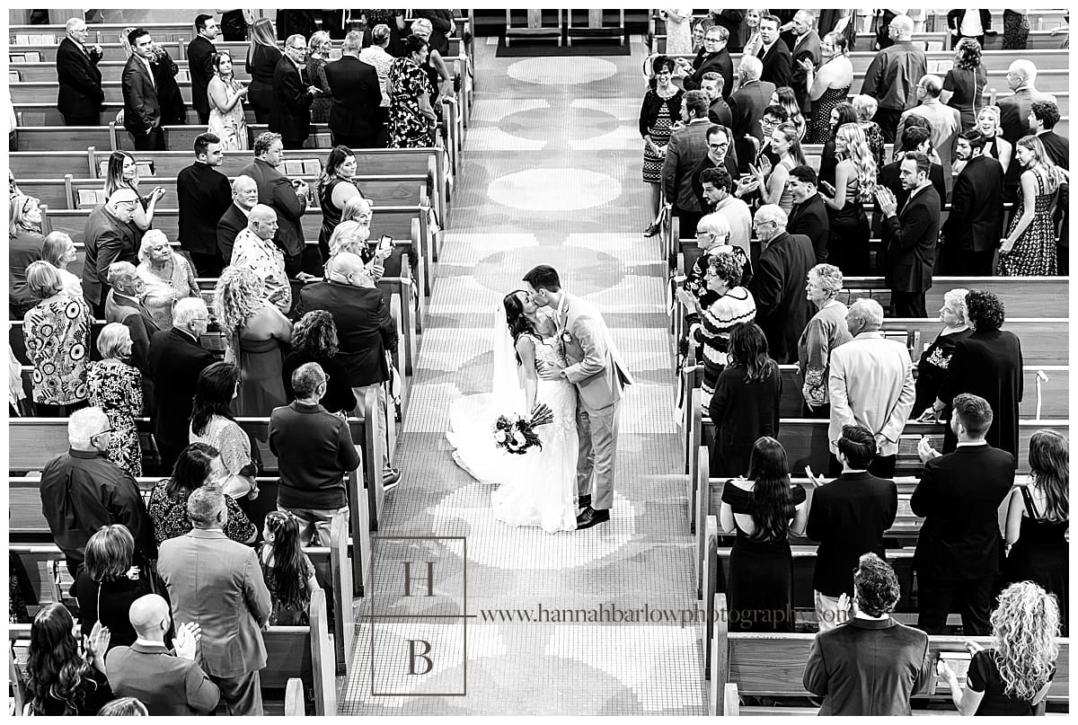 black and white photos of groom dipping bride in aisle of Catholic Church